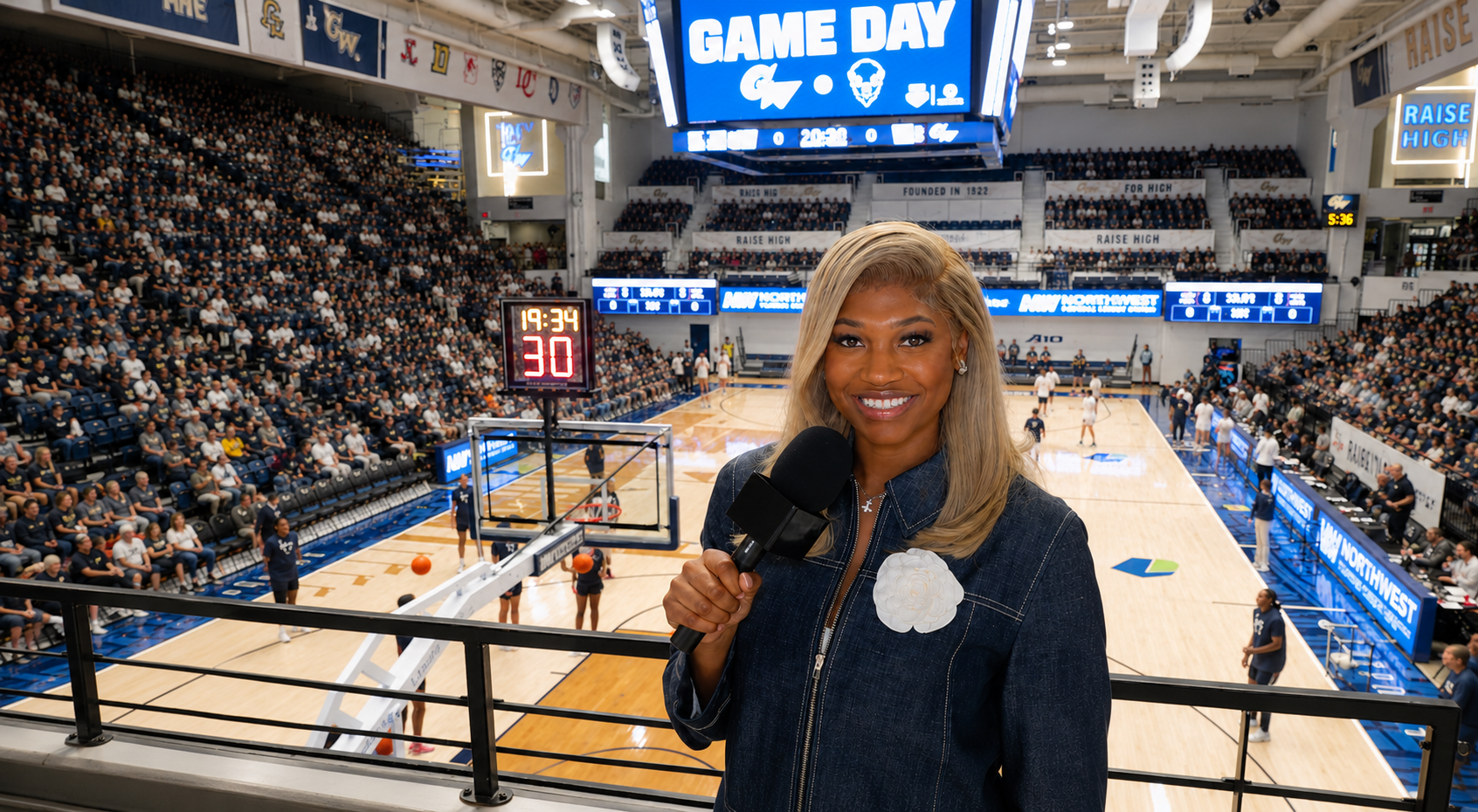 Jalynn Holmes holding a microphone on a balcony overlooking a Game Day basketball arena