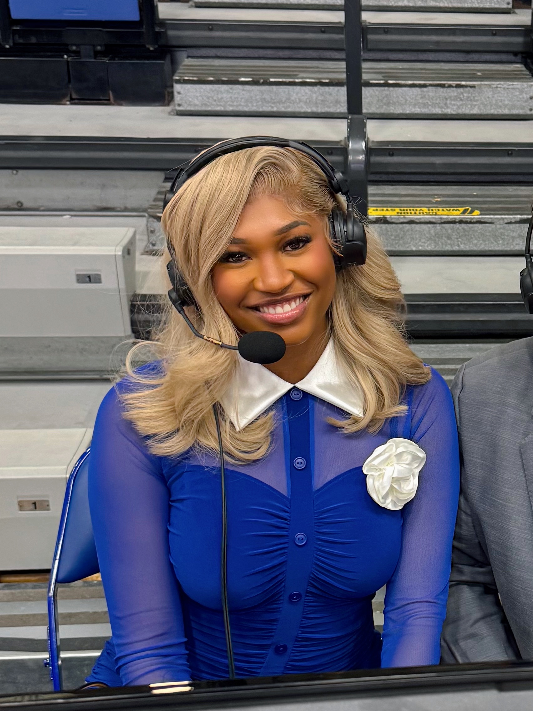 Jalynn Holmes wearing a broadcast headset at the arena announce table